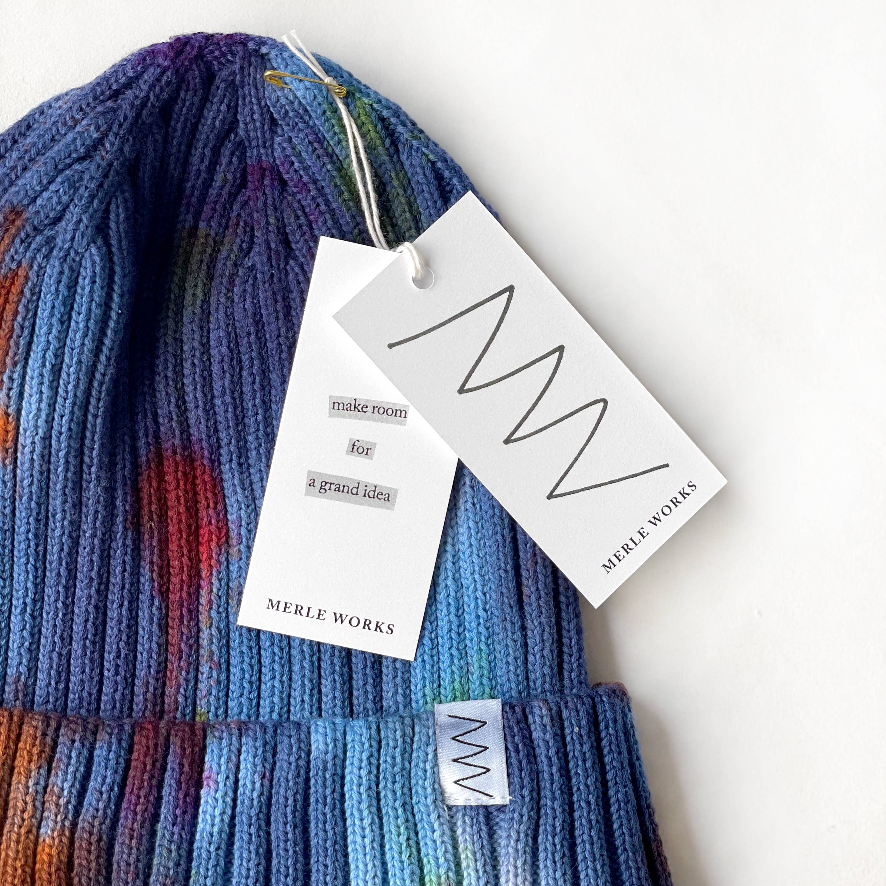 A blue hat with two white paper tags, laying against a white background.