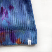 The detail of a blue beanie hat against a white background.