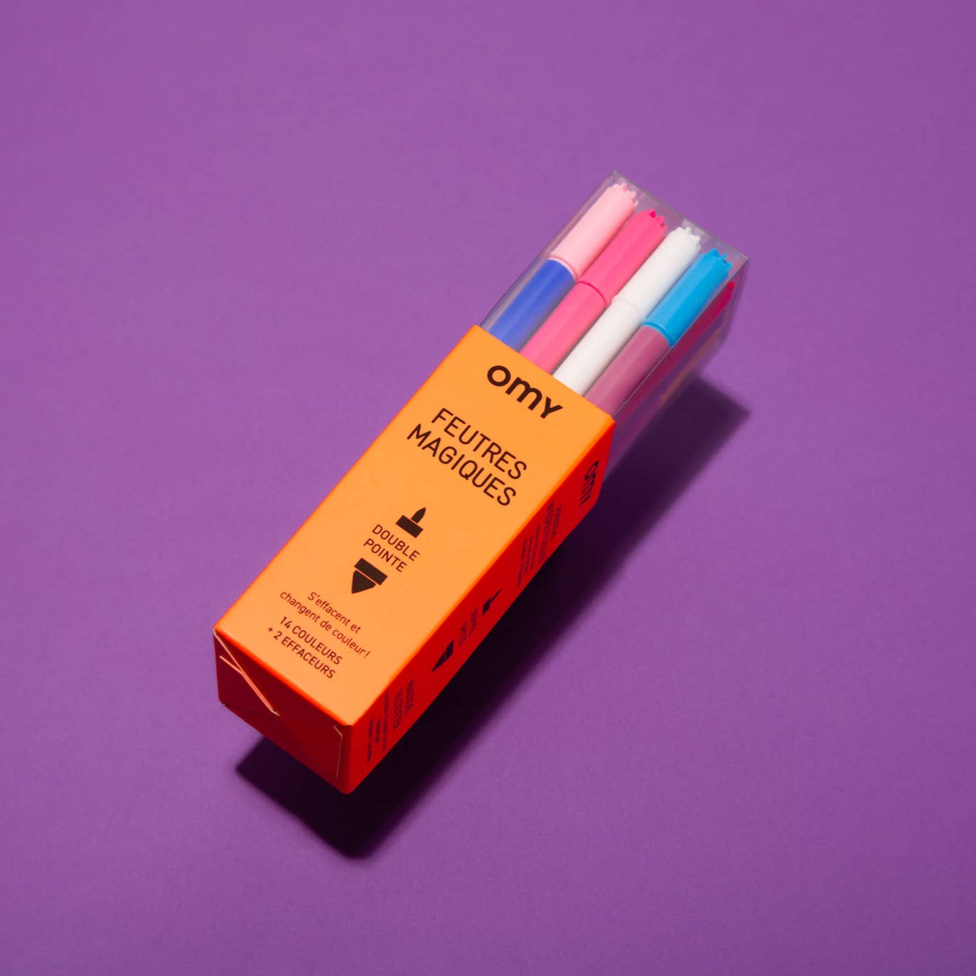 A set of OMY Magic Markers in various colors, with white caps, displayed in an orange box on a purple background.