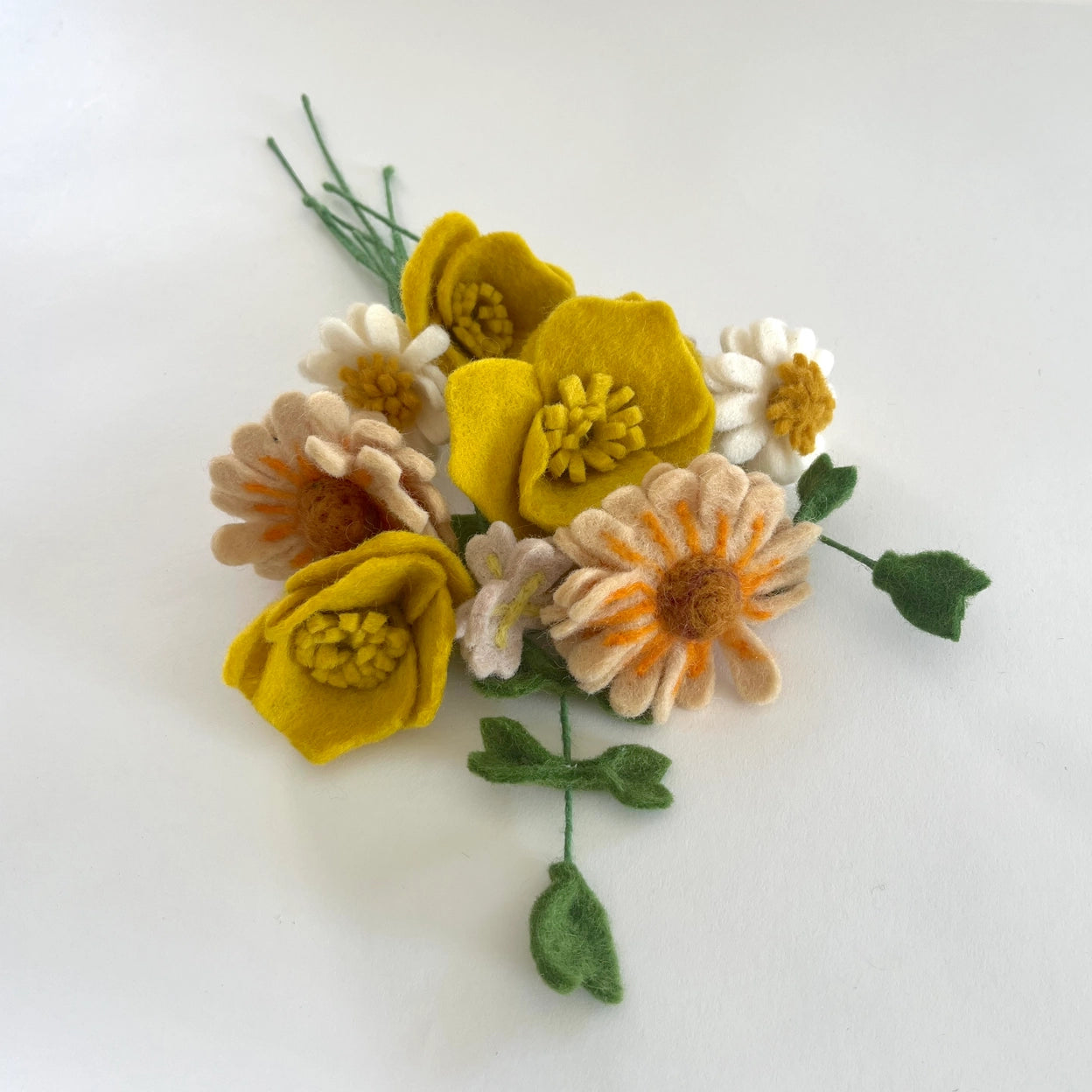Felt flower bouquet with yellow, orange, and white flowers on a white background