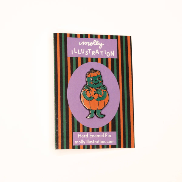 Halloween-themed pin featuring of a monster in an orange pumpkin on a striped cover.