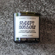 Candle labeled 'Sleepy Hollow' by Burnwell Illuminaries on a textured surface