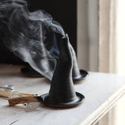 Incense cone burner with smoke on a wooden surface