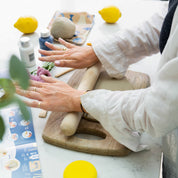 Person using a rolling pin on dough with lemons and other items on a table