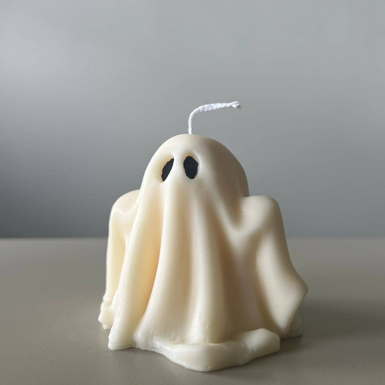 Ghost-shaped candle on a plain background