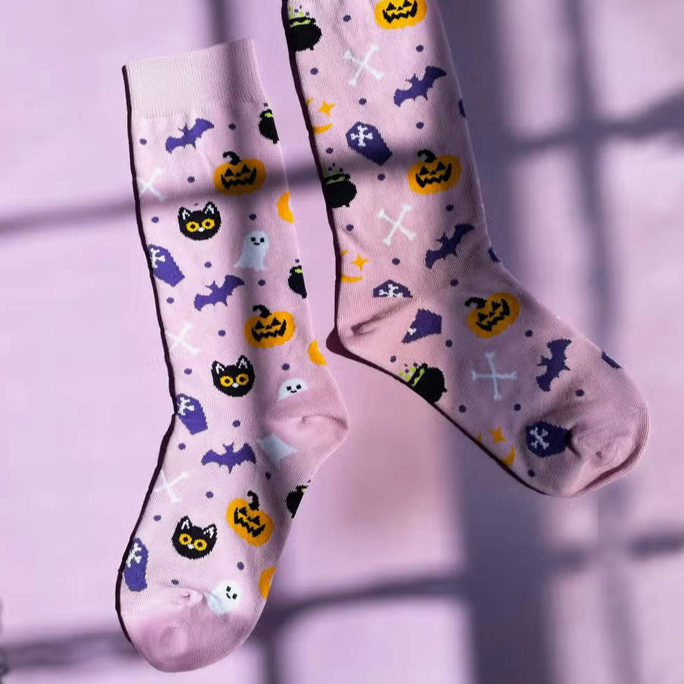 Purple halloween themed socks with cats, ghosts, bats and pumpkins on a purple background.