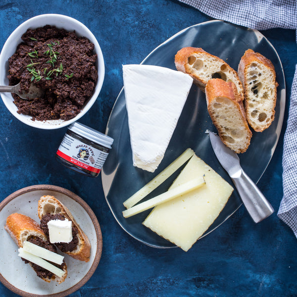 Platter with cheese, bread, and a spread on a blue surface