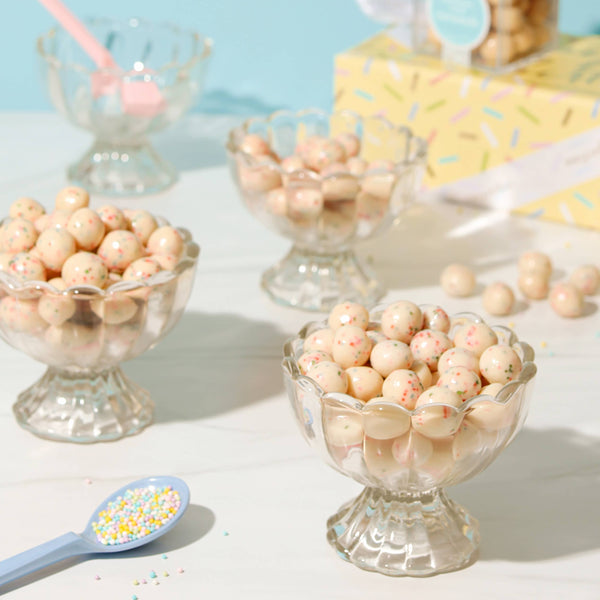 Decorative bowls filled with small round candies on a light surface with a blue background.