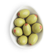 Green almonds with red spots in a white bowl on a white background