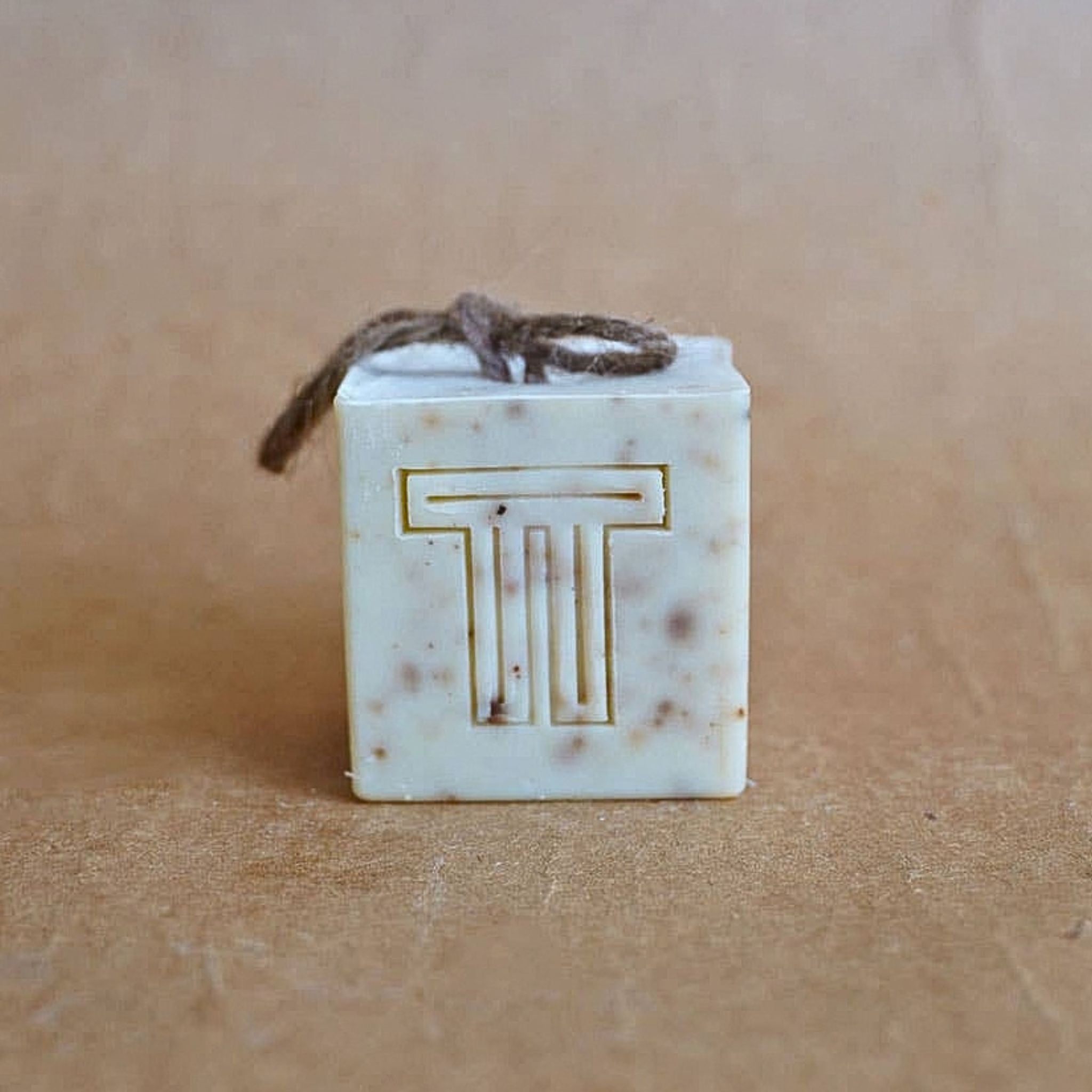 A square bar of soap with the letter T on it, and a natural string.