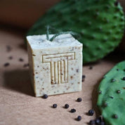 A square bar of Terra Tory soap on a natural background with a cactus and black peppercorns.