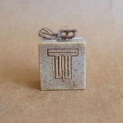 A square bar of soap marked with two T's and a natural string on top.