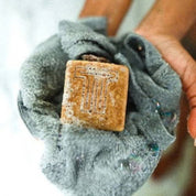 Gray towel with a sudsy bar of soap inside on a white background