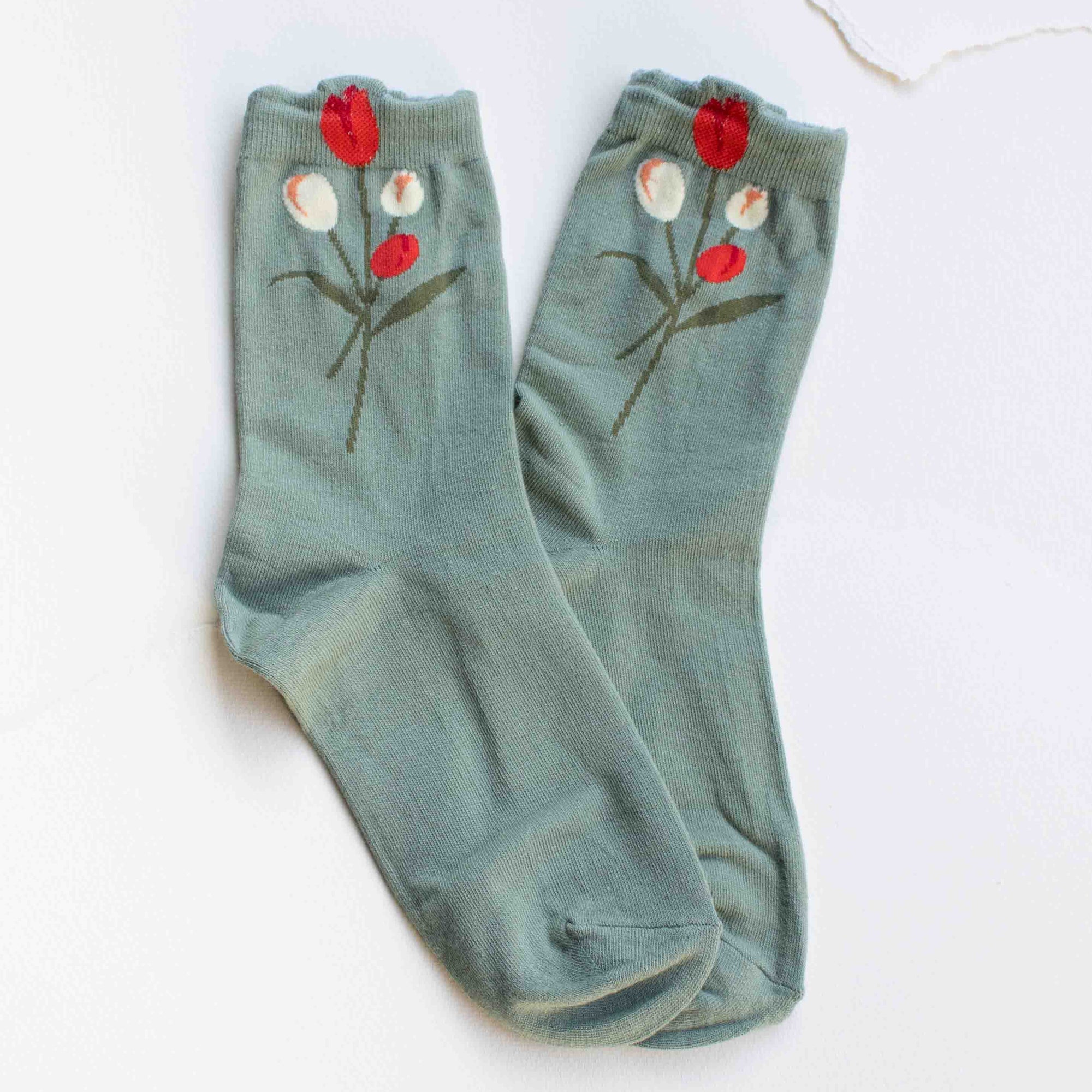 Pair of sage green socks with floral designs on a white background