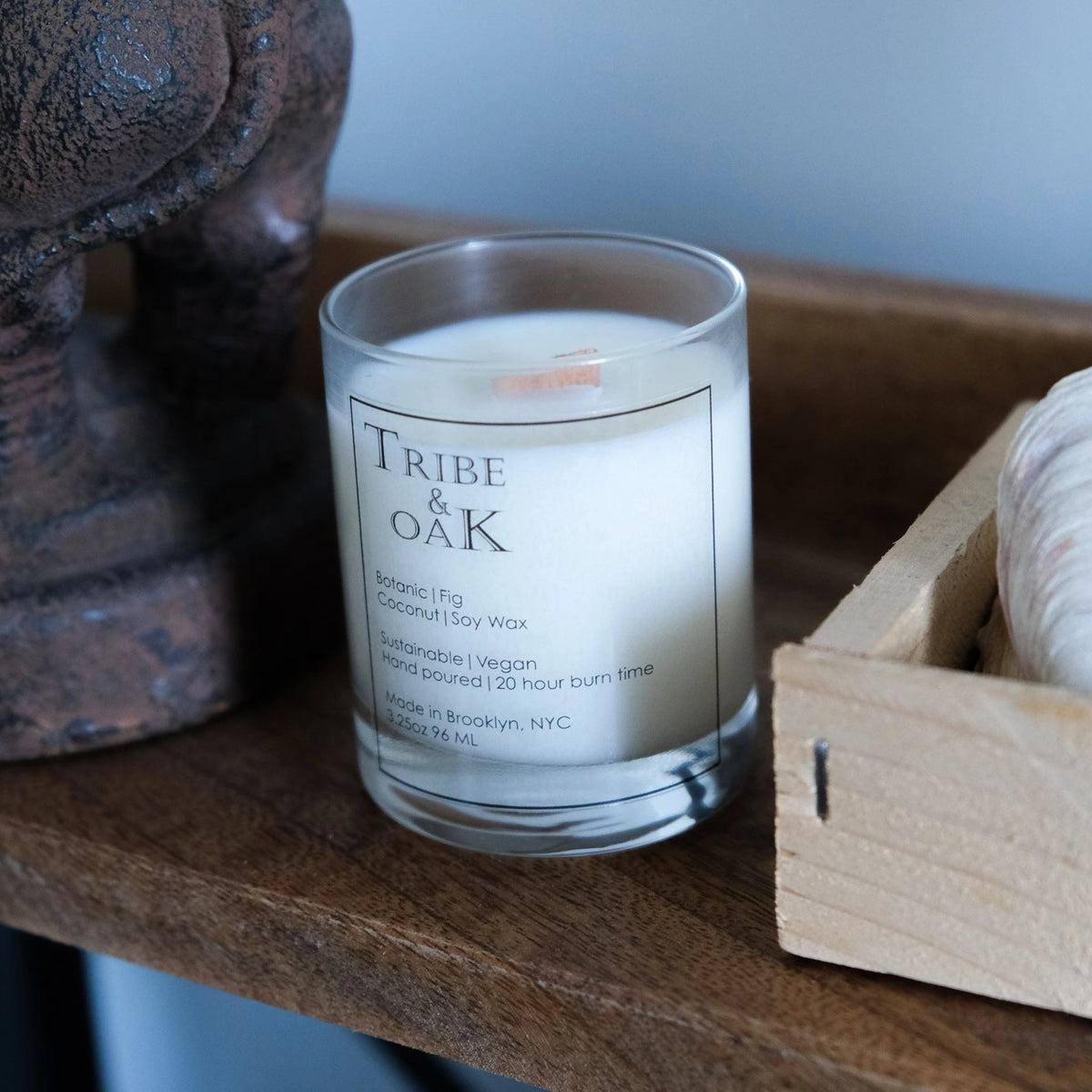 Candle labeled 'Tribe of Oak' on a wooden shelf with decorative items.