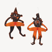 Two Halloween hanging ornaments shaped like witch cats, one standing and one crouching, both in black with orange tutus and white hanging loops, shown on a plain white background.
