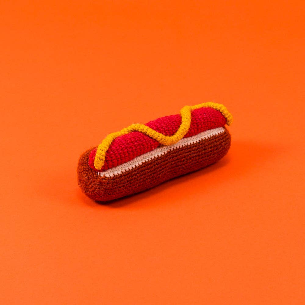 Knitted hot dog toy on an orange background
