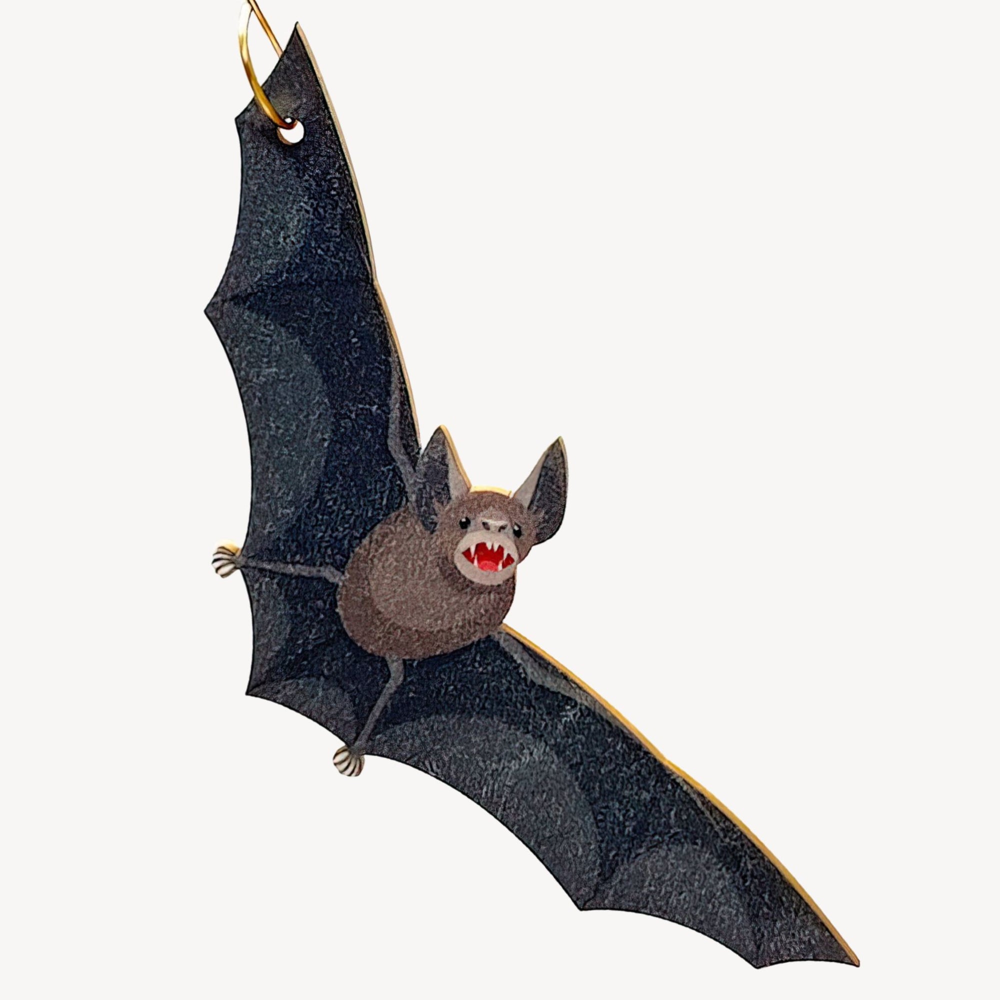 Bat-shaped ornament hanging from a gold hook on a white background.