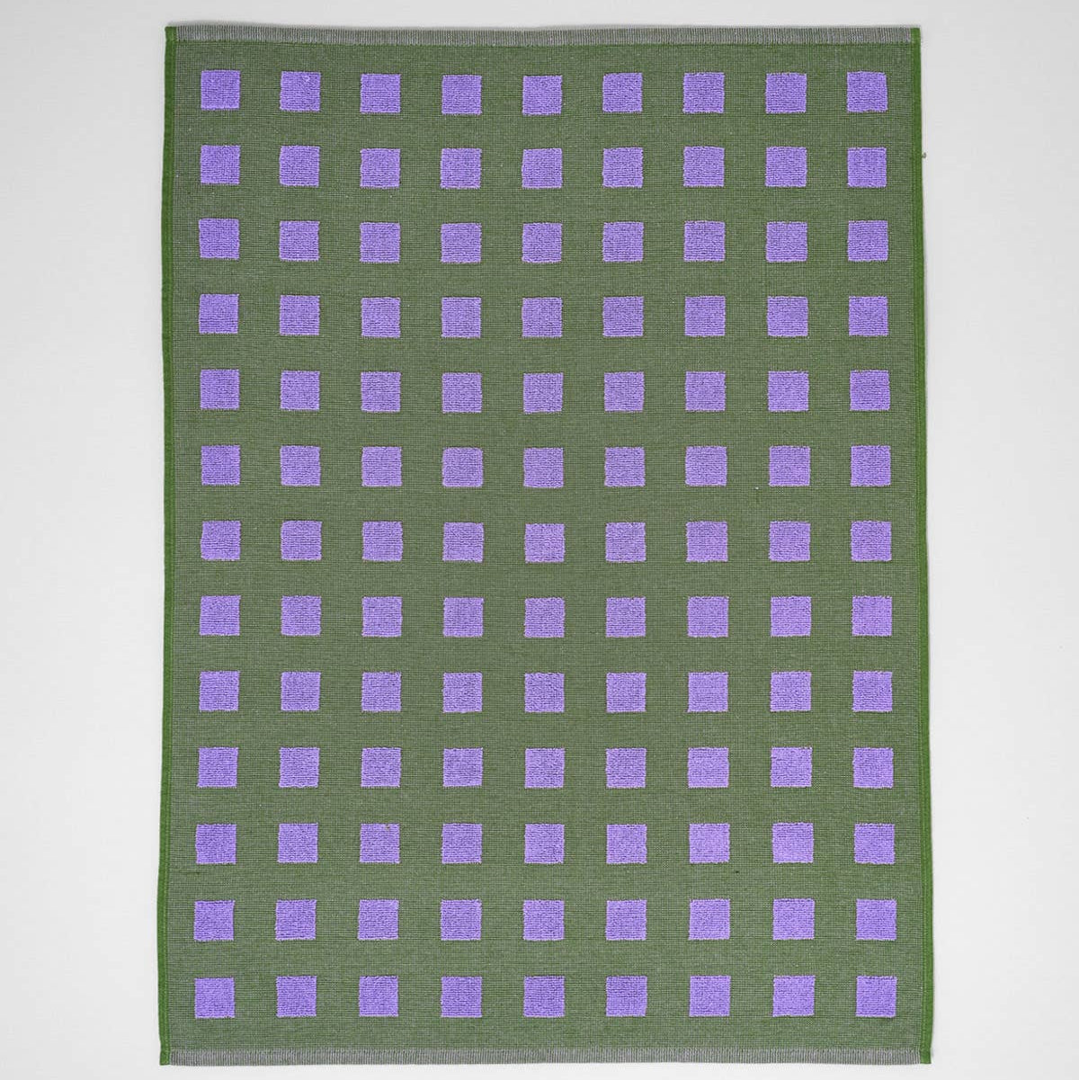 Green fabric with purple square pattern on a white background