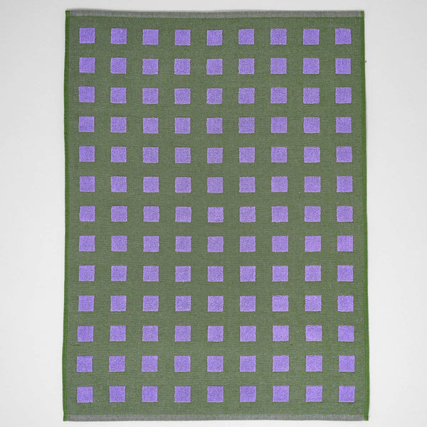 Green fabric with purple square pattern on a white background