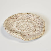 Speckled ceramic bowl on a light gray background