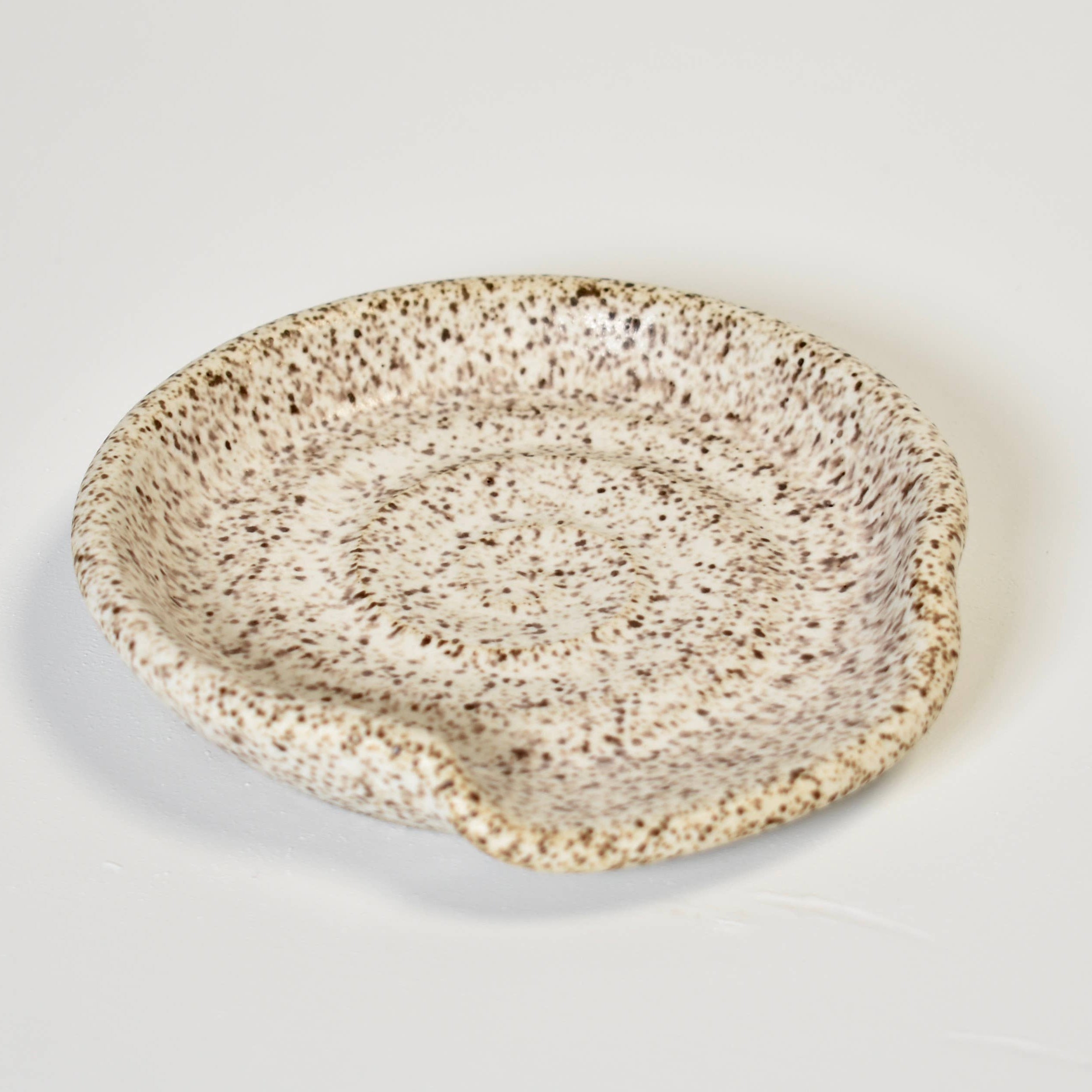 Speckled ceramic bowl on a light gray background