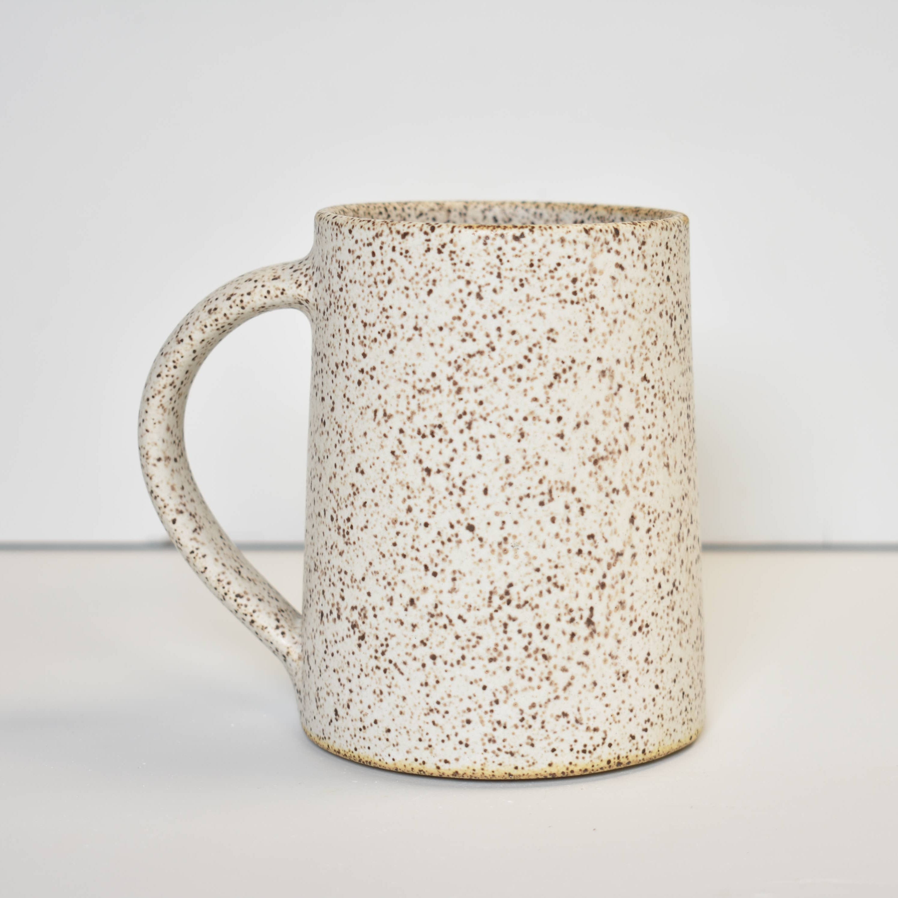Speckled cream ceramic mug on a plain background