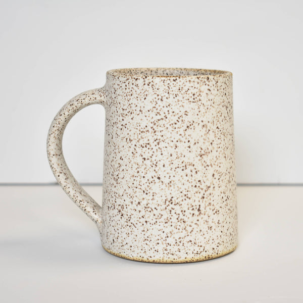 Speckled cream ceramic mug on a plain background