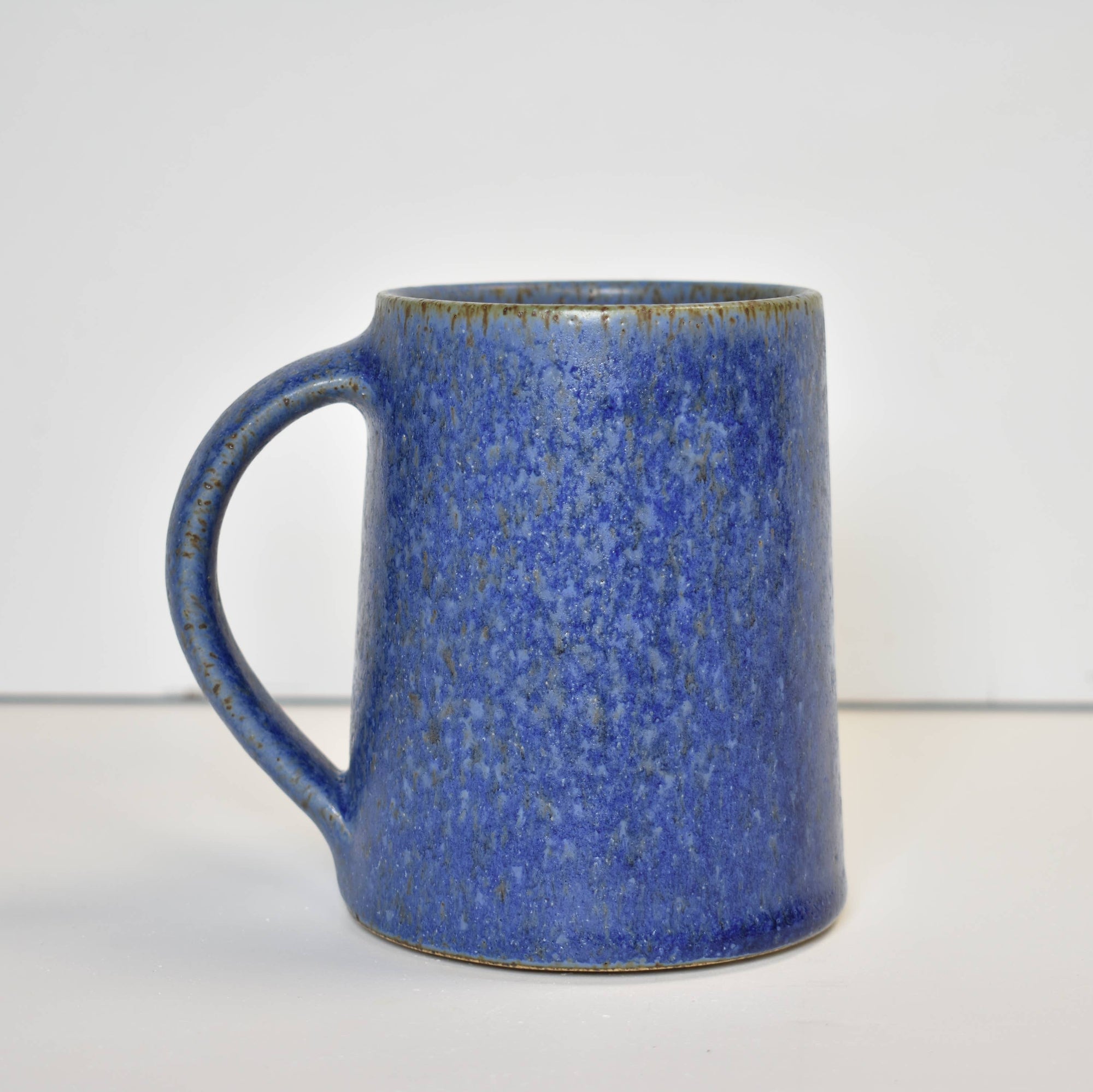 Blue speckled ceramic mug on a white background
