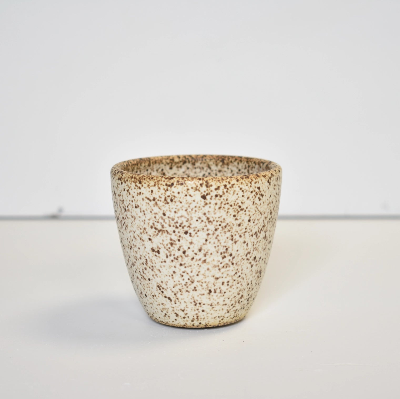 Speckled ceramic cup on a plain background