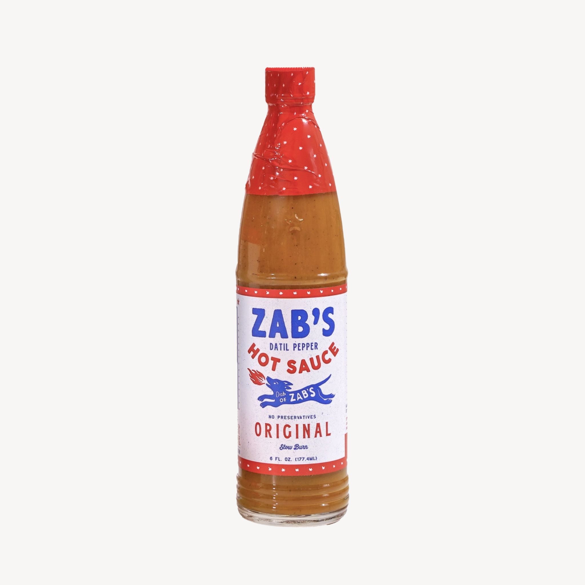 A bottle of Zab's Hot Sauce, Original, featuring a white label with blue and red text, a red cap, and a red patterned neck sleeve, containing a reddish-brown sauce, set against a plain light gray background.