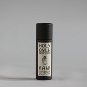 Holy Oylh Raw Lip Balm in Peppermint, in a matte black cylindrical container with a white label, set against a neutral gray background.